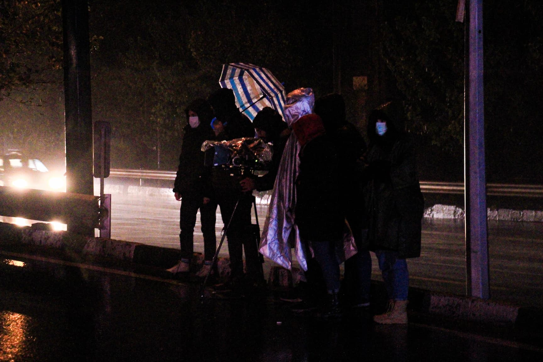 waken short film crew stanfing by the freeway under heavy rain